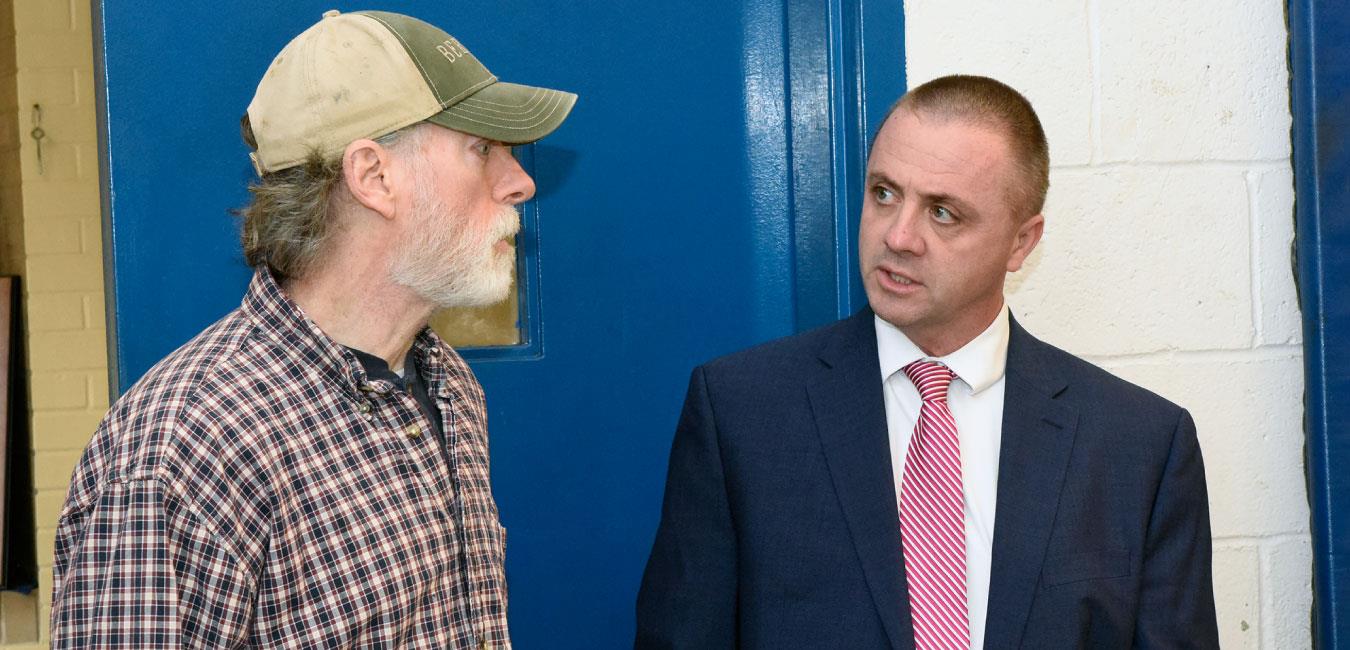 Representative Deasy speaking to middle aged man wearing baseball hat