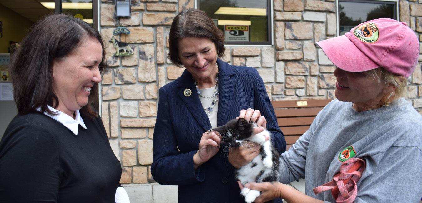 Representative Madden petting kitten with next to two smiling women