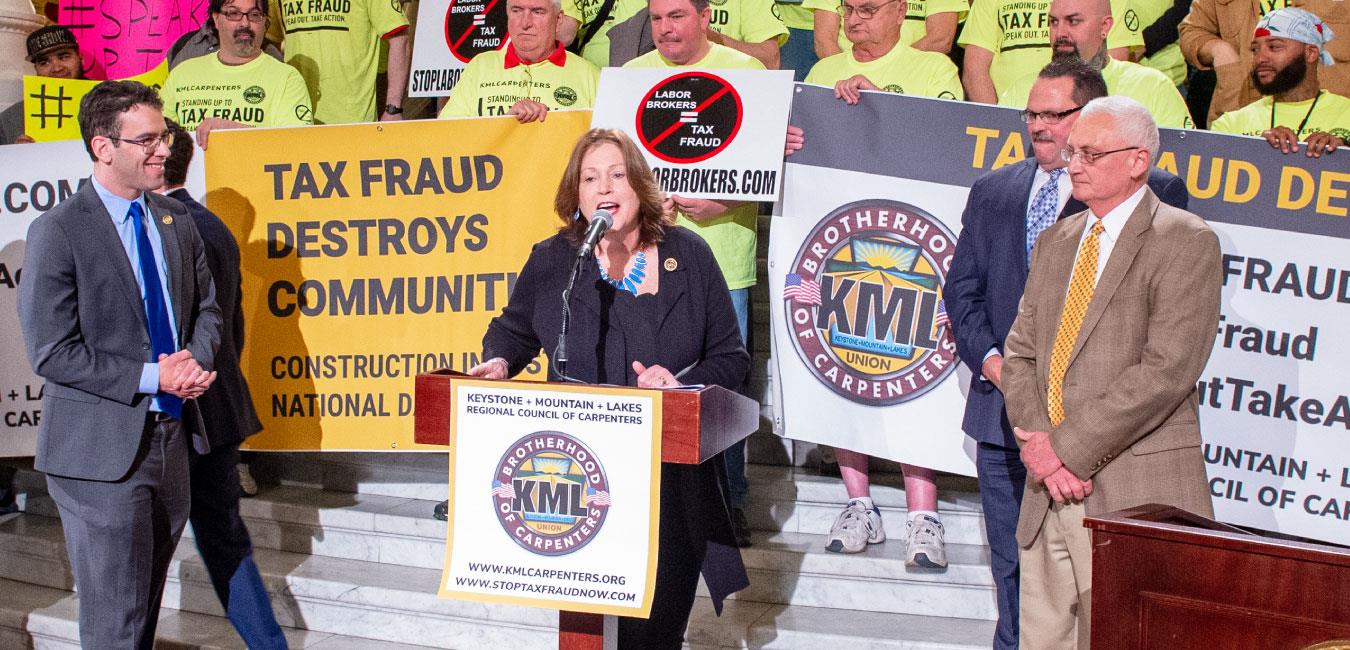 Representative McNeill speaking at podium in front of members of Brotherhood of Carpenters on Capitol rotunda steps