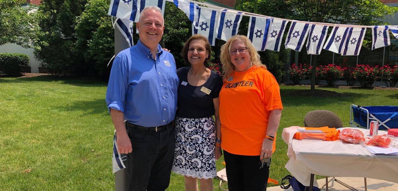 Representative Warren posing for photo with two women volunteering at outdoor event