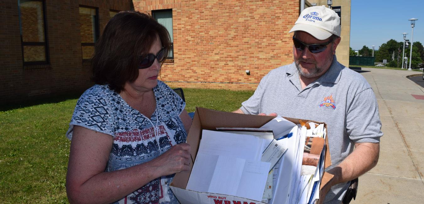 Man handing box of papers to Representative McNeill at paper shredding event