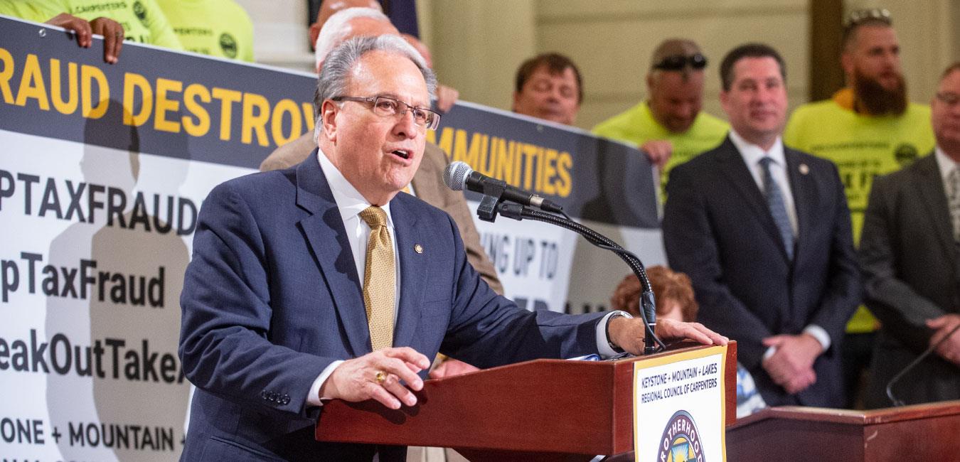 Representative Pashinski speaking at podium in front of Brotherhood of Carpenters rally on Capitol rotunda steps