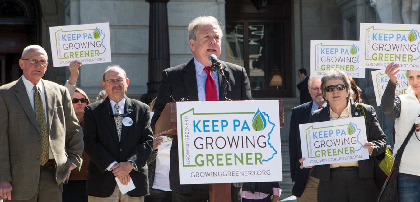 Representative Freeman standing in front of people on Capitol steps holding signs reading Keep PA Growing Greener