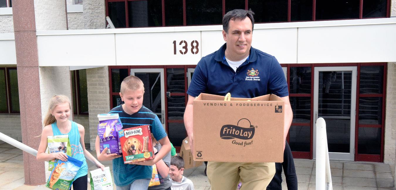 Representative Burns and children carrying boxes of pet food and supplies