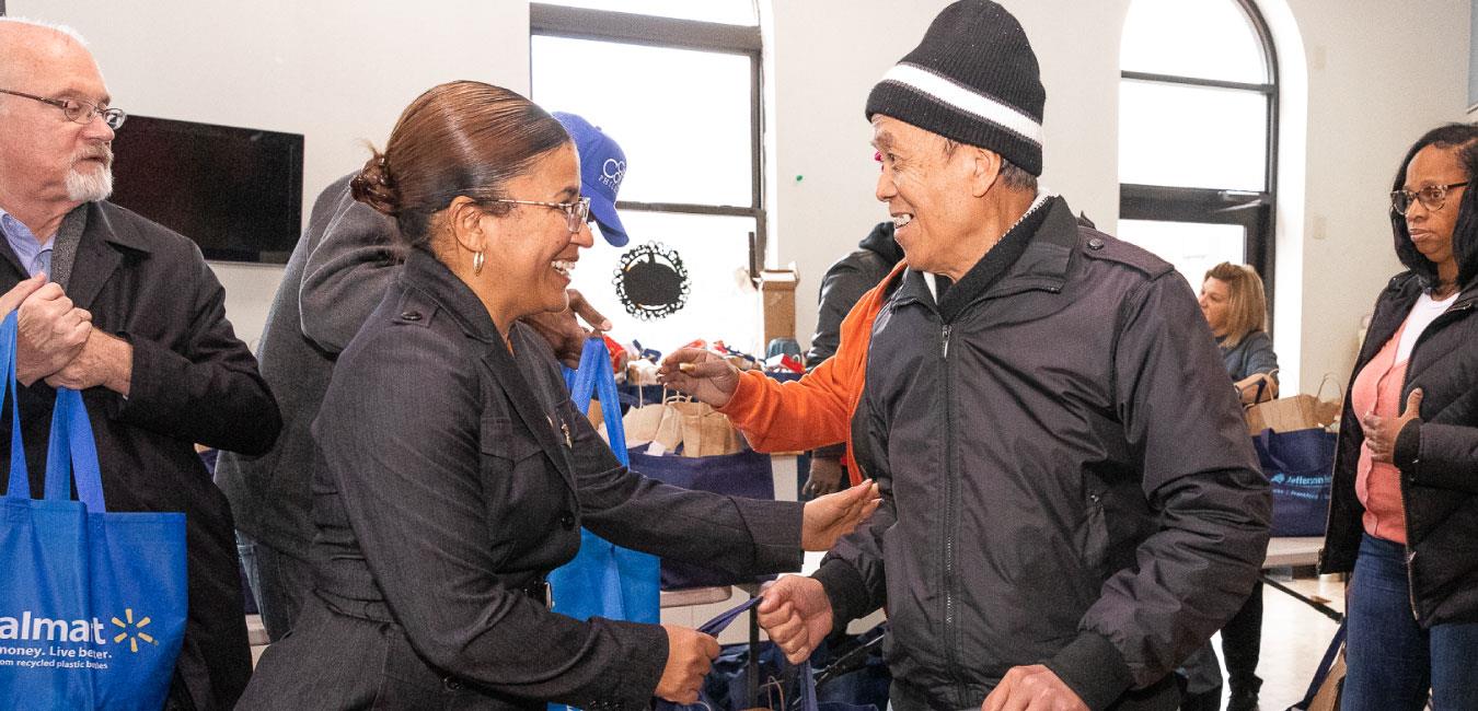 Representative Bullock handing bag to and smiling at man at event for senior citizens