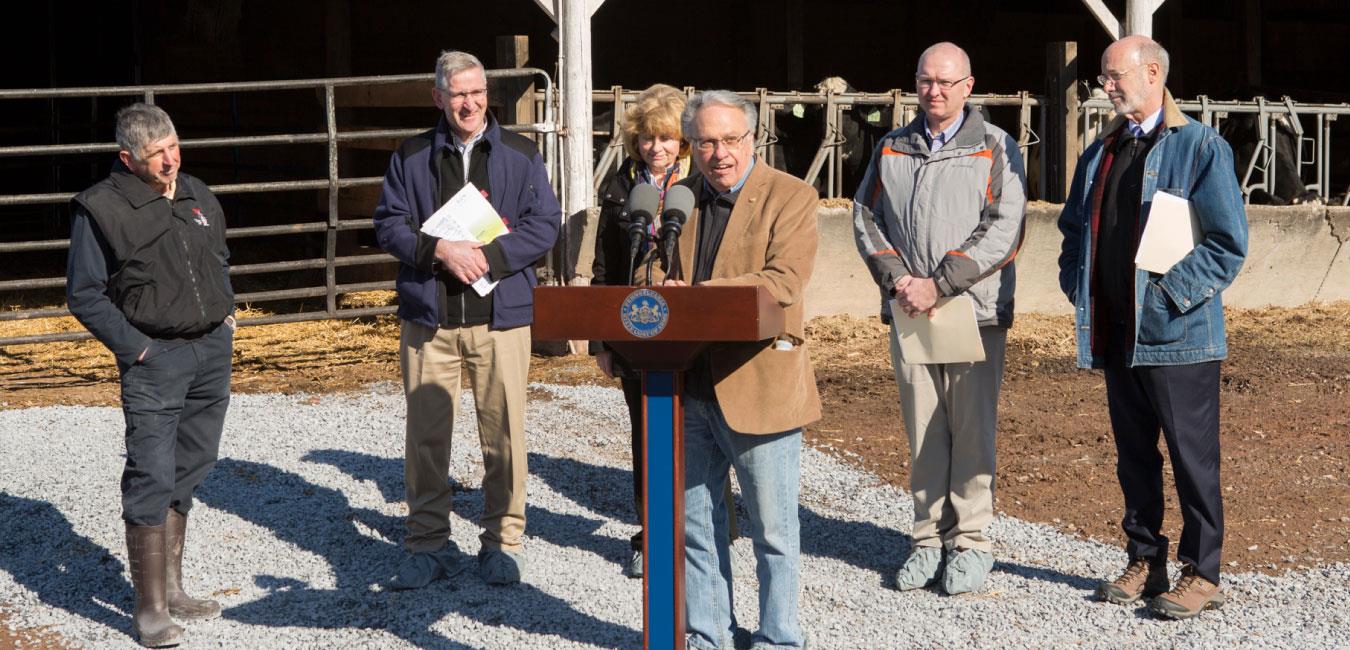 Representative Pashinski speaking at podium in front of Governor Wolf, Secretary Redding, and officials at farm