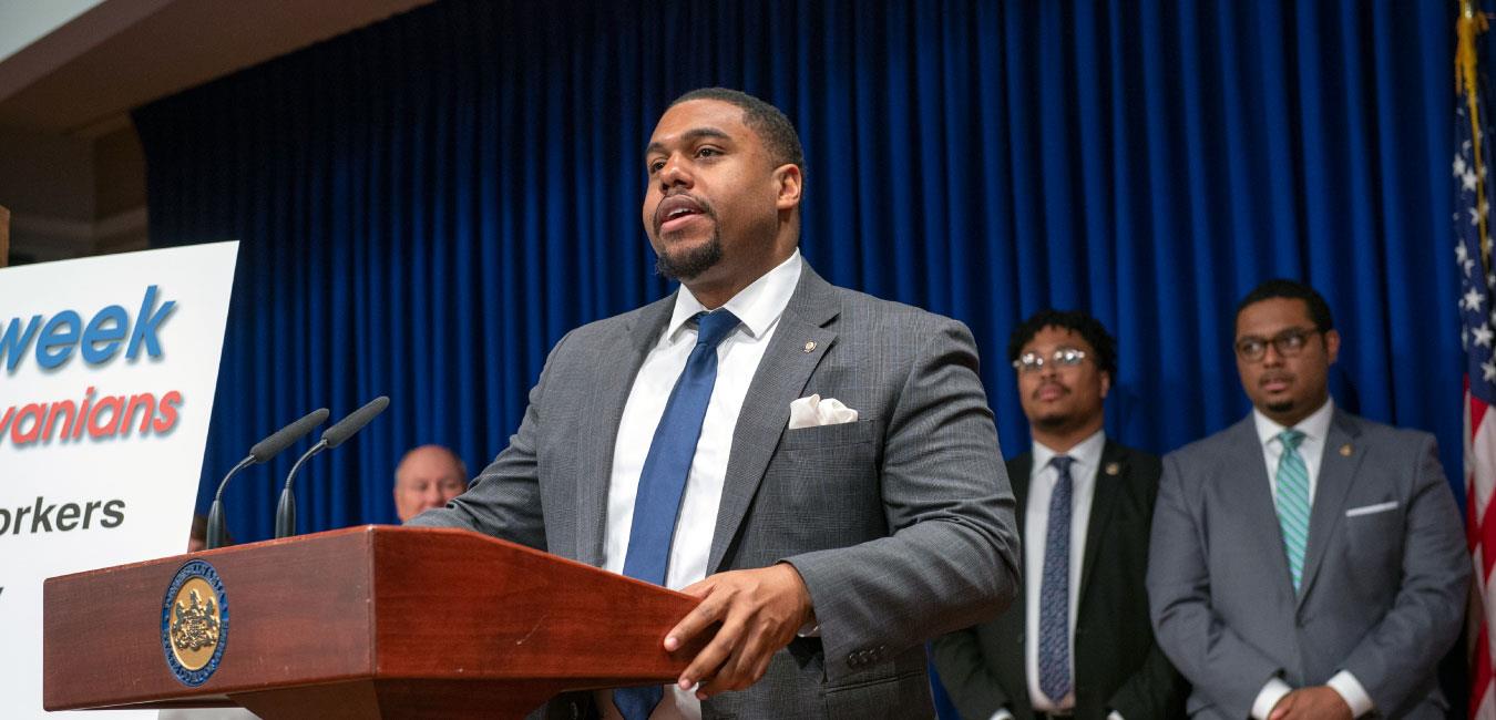 Representative Dawkins speaking at podium in front of fellow legislators at news conference in Capitol Media Center