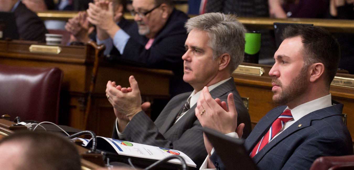 Representative Conklin sitting next to Representative Bizzarro on House floor and applauding