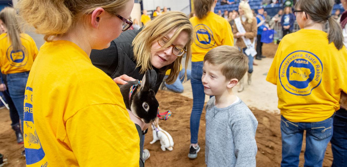 Representative Krueger at Farm Show with children wearing PA State Rabbit t-shirts and petting rabbit