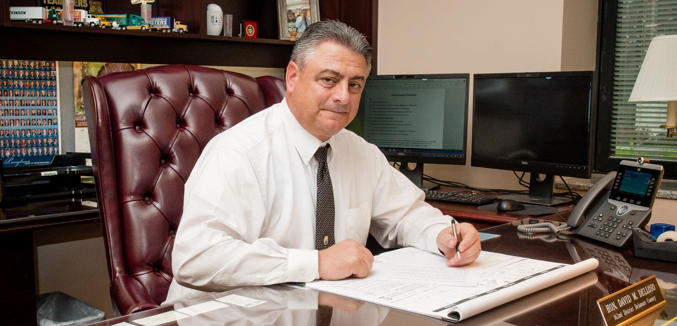 Representative Delloso sitting at desk posing for photo