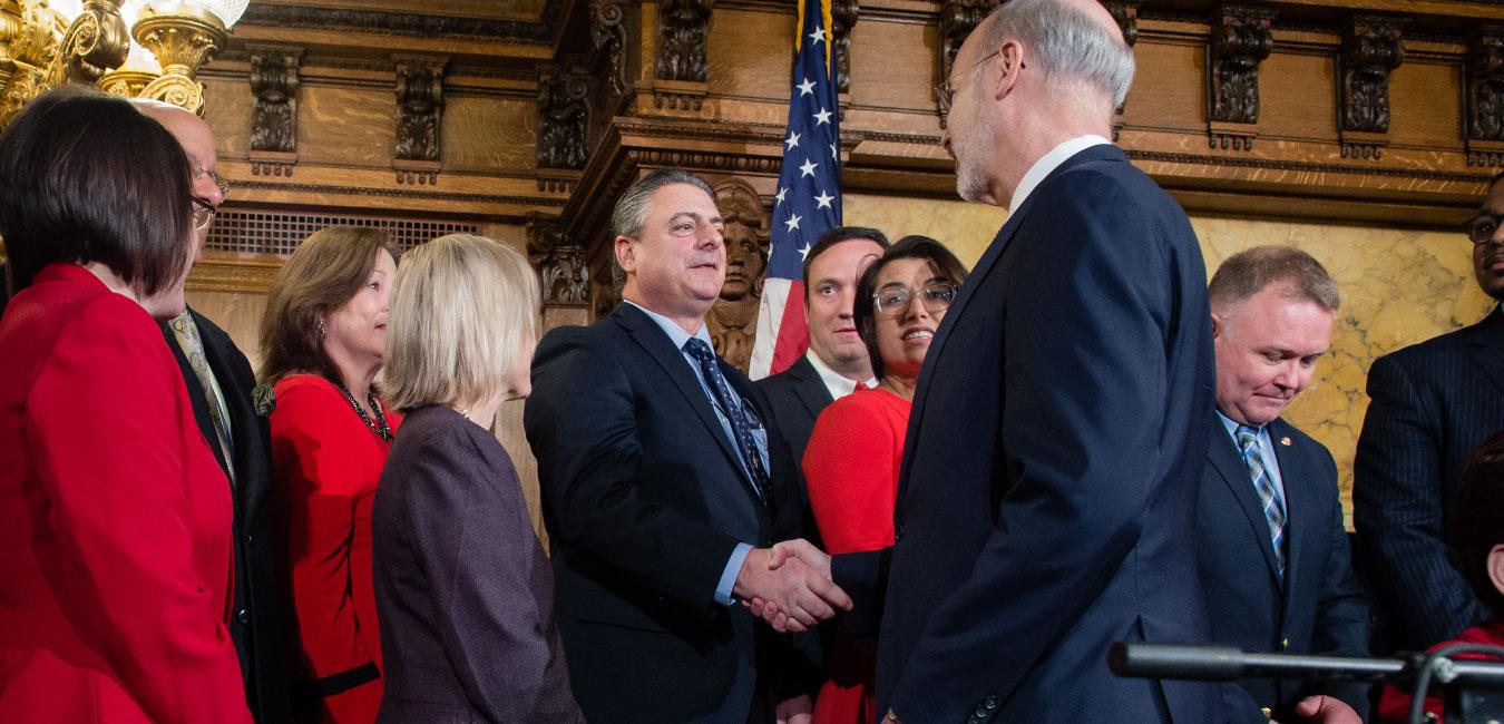 Representative Delloso standing next to fellow legislators in Governor’s Reception Room and shaking hands with Governor Wolf