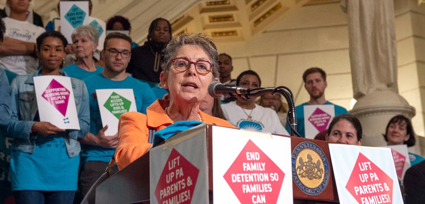 Representative Daley speaking in front of activists on Capitol rotunda steps at news conference