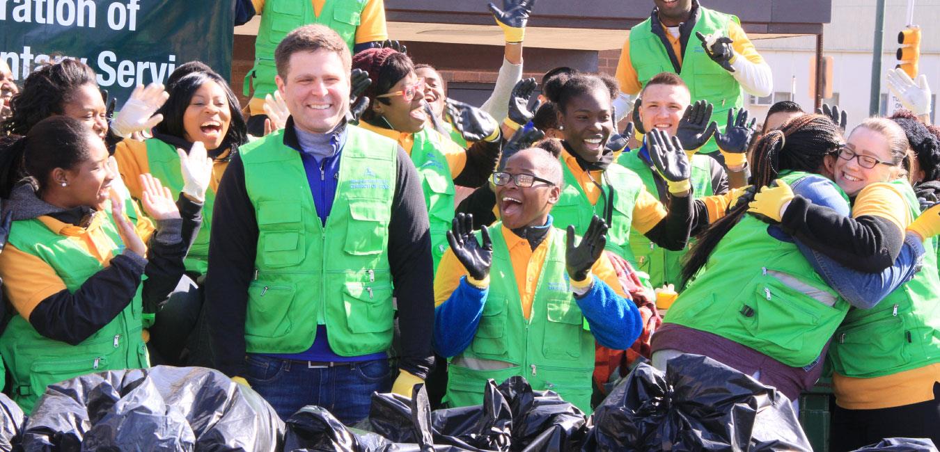 Representative Solomon wearing green vest and smiling with group of happy volunteers