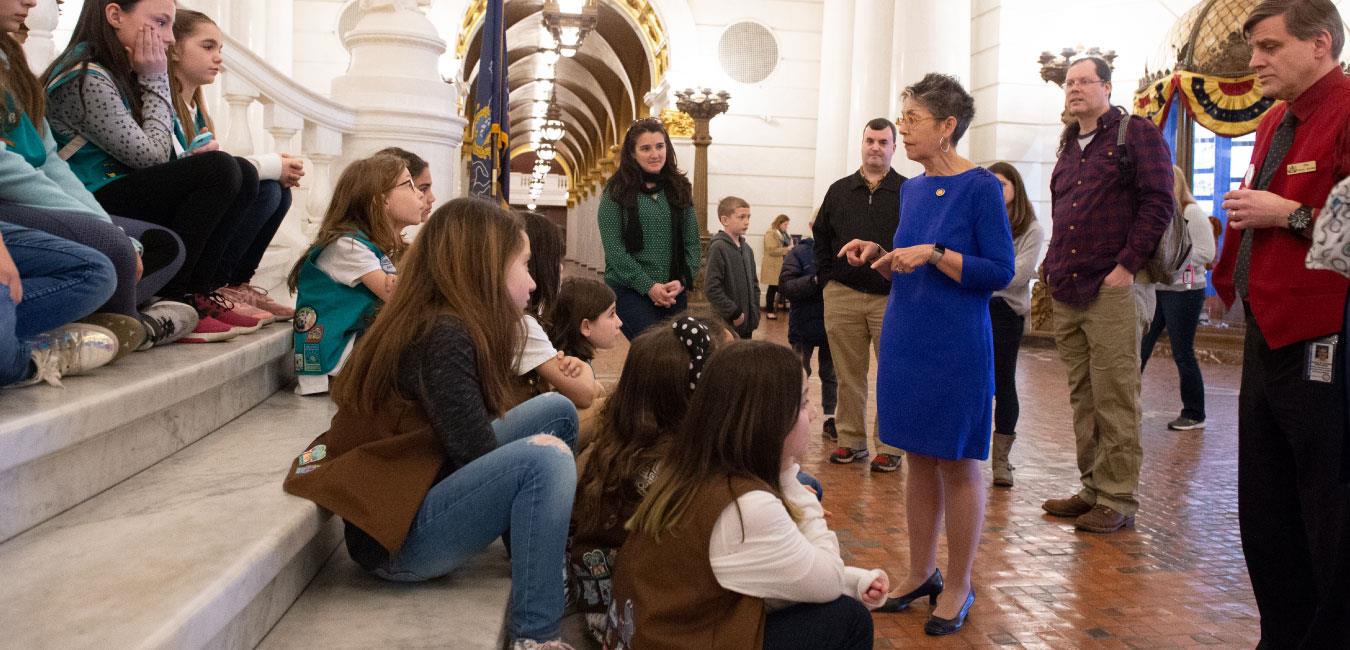 Representative Daley speaking to Girl Scouts troop sitting on Capitol rotunda steps