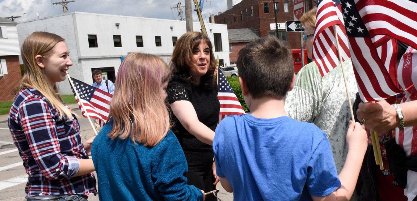 Representative Kulik shaking hands with group holding American flags