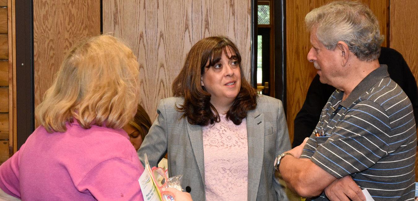 Representative Kulik speaking to woman and man next to wooden door