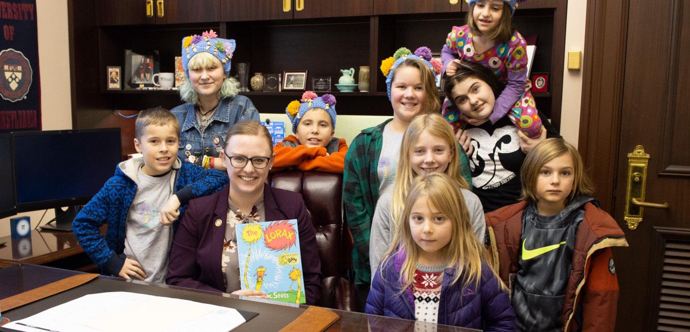 Representative O’Mara holding Dr. Seuss’s The Lorax and posing for photo with young students in her office