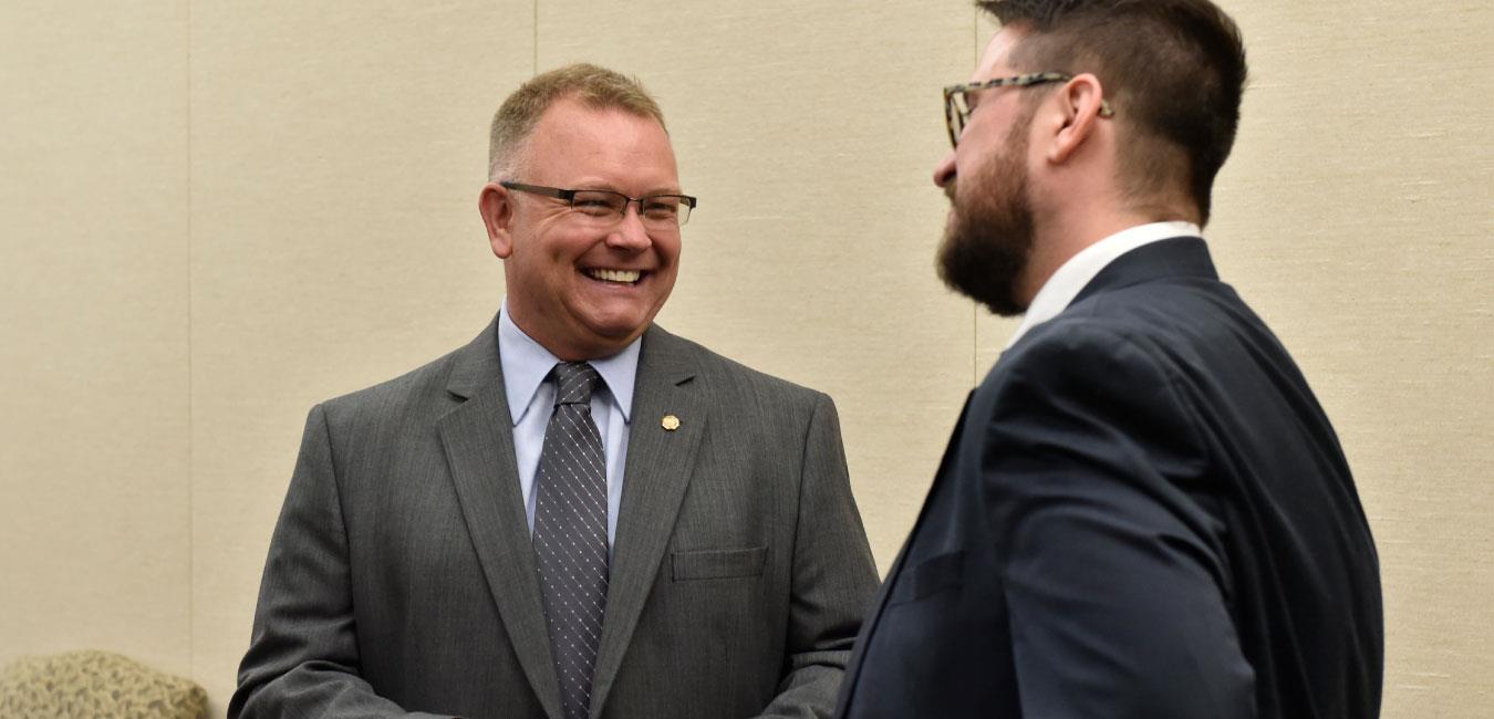 Representative Harkins smiling and speaking to man