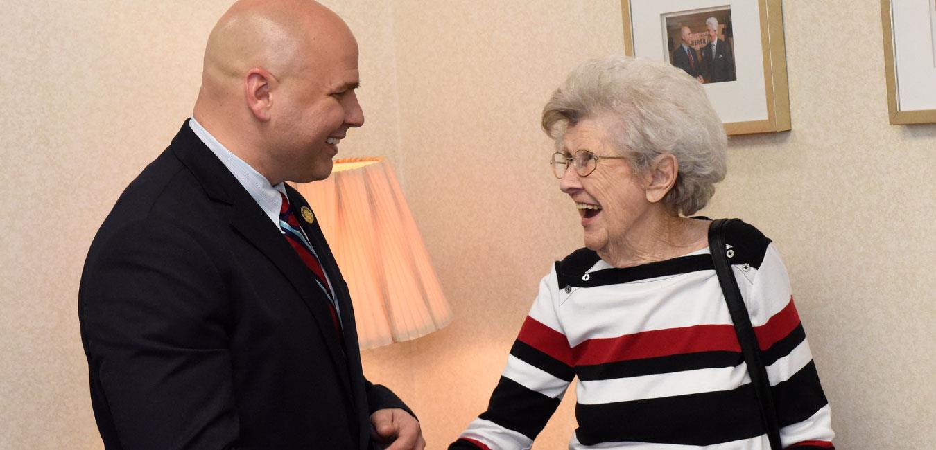 Representative Merski speaking to elderly woman who is laughing