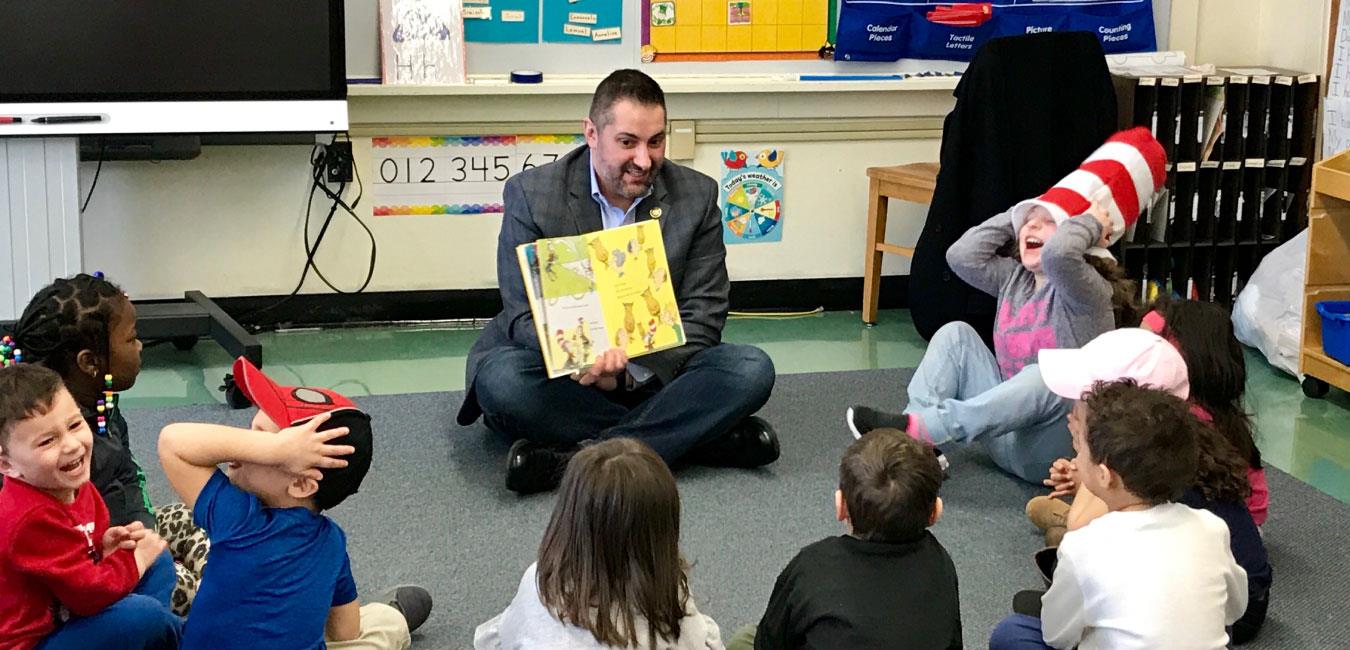 Representative Malagari reading Dr. Seuss book to group of young children