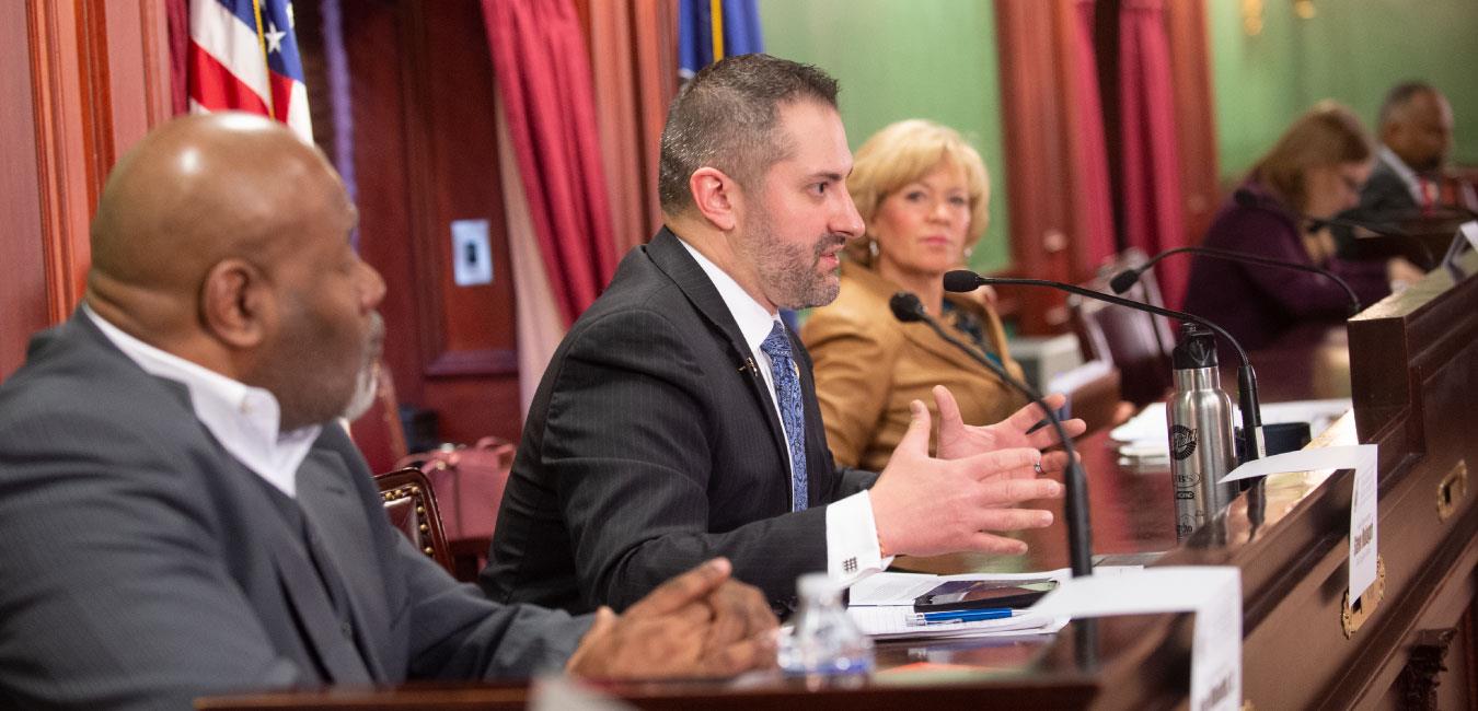 Representative Malagari speaking into microphone at hearing