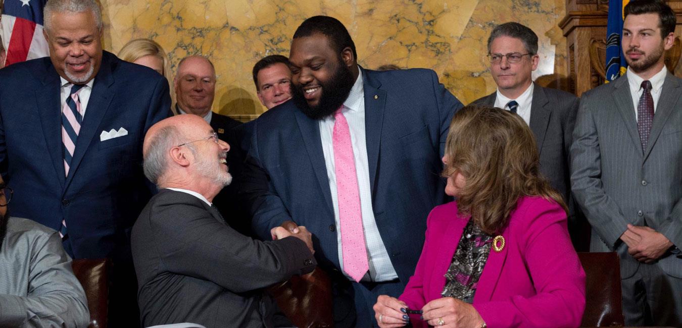 Representative Harris smiling and shaking hands with Governor Wolf next to fellow legislators in Governor’s Reception Room