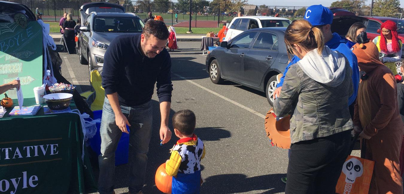 Representative Boyle handing out candy to young boy dressed as Toy Story’s Woody for Halloween