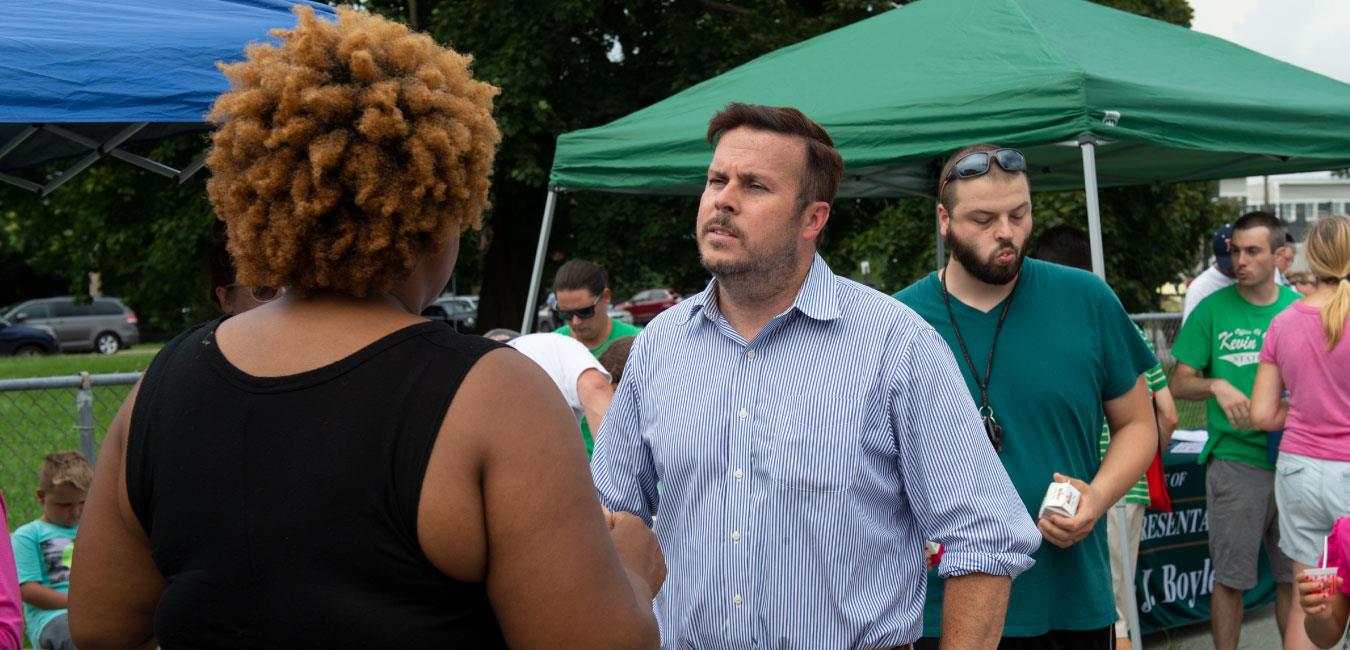 Representative Boyle speaking to constituent next to tent at outdoor event