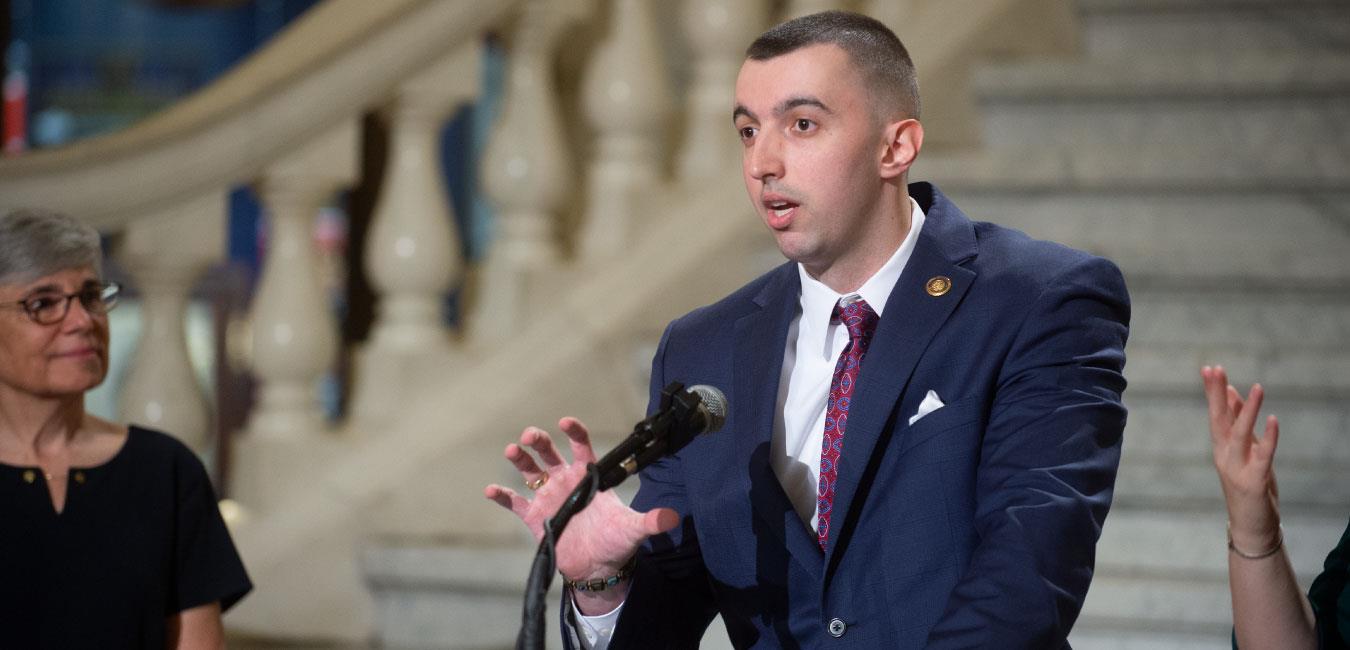 Representative Markosek speaking at podium in front of Capitol rotunda steps